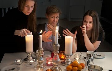 Tre kvinder sidder ved stearinlys