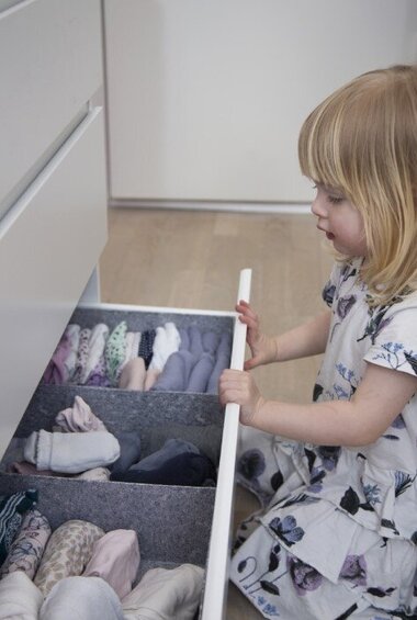 2-årige Benedikte ved kommode, hvor tøjet er foldet sammen i skuffen