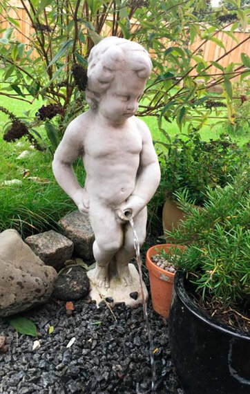 Manneken Pis står ved siden af krukker og tisser ned i sten Manneken Pis står ved siden af krukker og tisser ned i sten