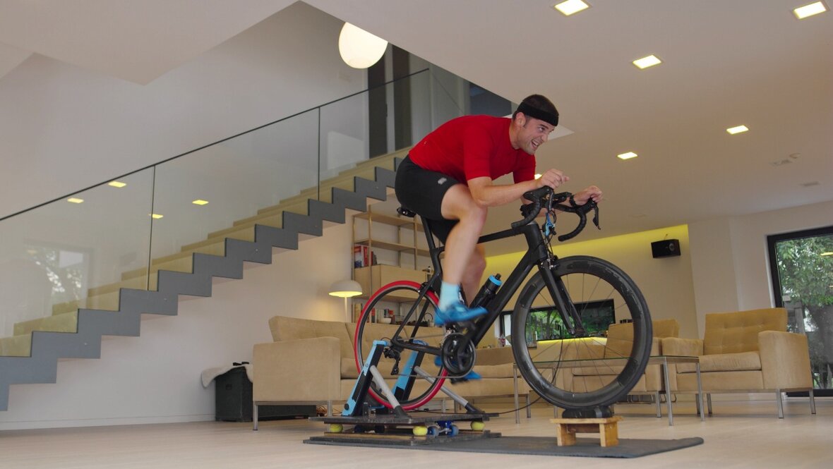 Mand cykler på hometrainer i stue