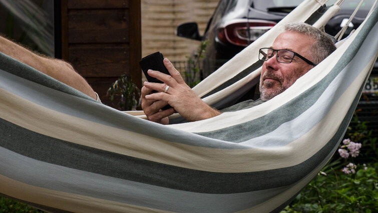 Peter ligger i hængekøje og kigger på telefonen