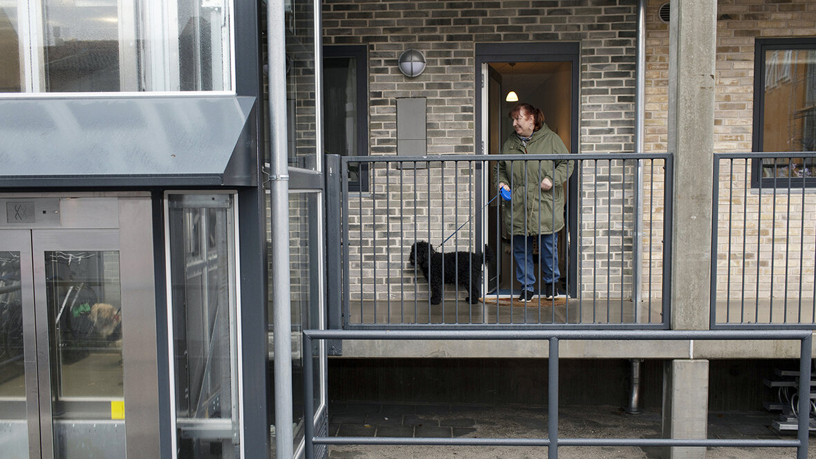 Kvinde udenfor sin lejlighed med hund i snor