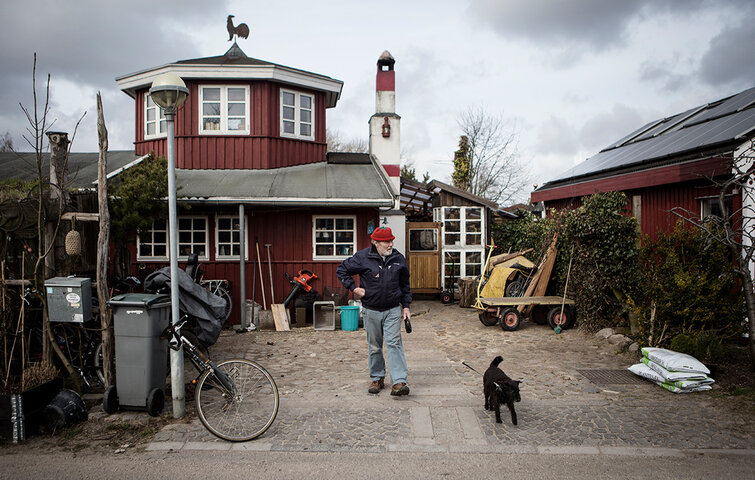 Gert Iversen går tur med hunden foran sit hus.