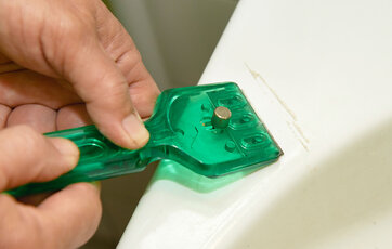 En skraber kan fjerne kalkbelægning på toilettet.