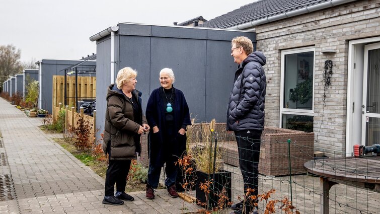 Beboere i samtale foran huse i bofællesskabet Sundhaven
