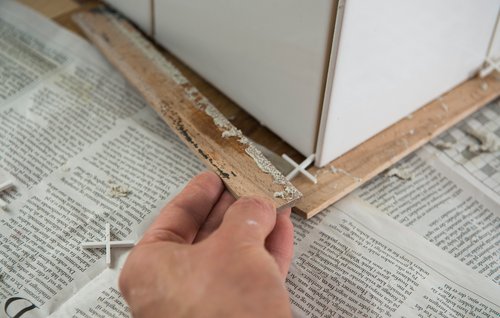 Understøttende pinde mellem bordplade og nye fliser på væg fjernes