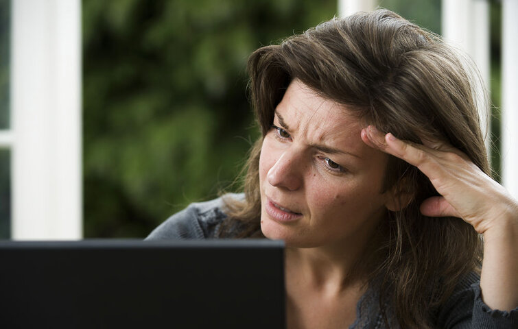 Kvinde kigger skeptisk på sin pc-skærm