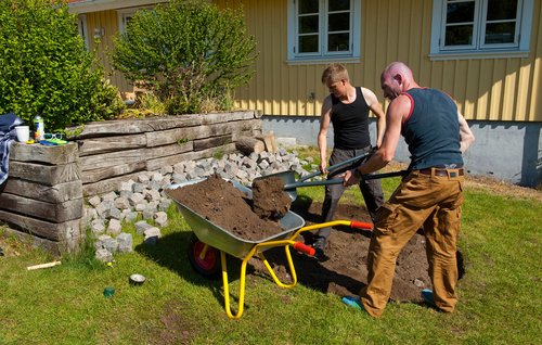 Græs og jord køres væk i trillebør