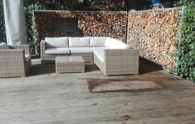 Havemøbler placeret foran brændevæg på terrasse