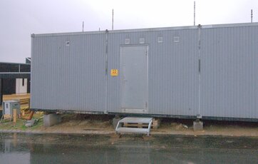 Grå skurvogn stående på betonklodser