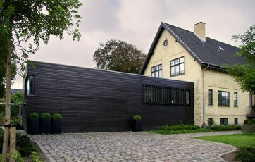 Detalje i facade, hvor der går et gitter af træ foran vinduerne.