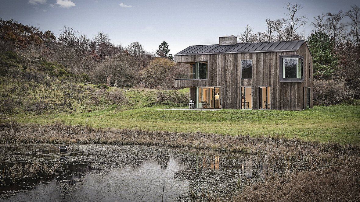 Træhus med facade i grantræ beliggende i naturområde ved skov