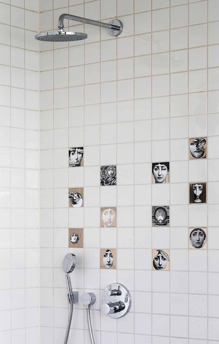 Fliseinspiration9 En bruseniche med hvide, kvadratiske fliser og enkelte kunstfliser med ansigter.