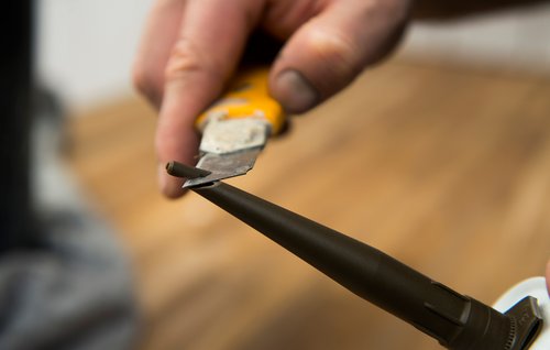 Toppen af patron med silikonefuge skæres skråt af med hobbykniv