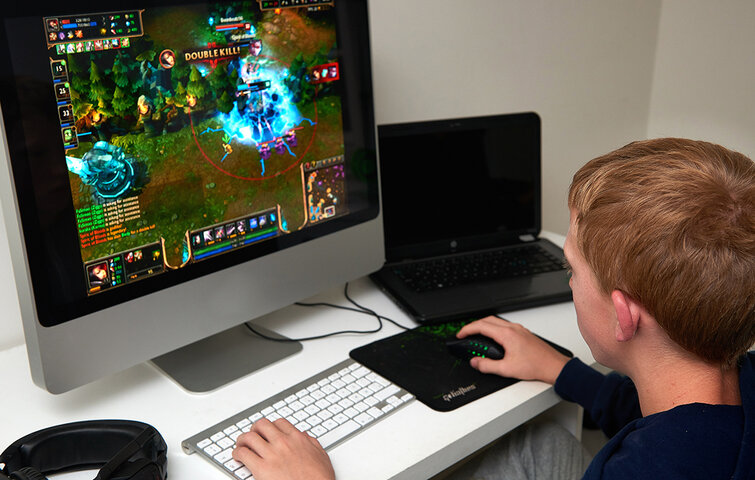 Dreng spiller computer foran skærm.