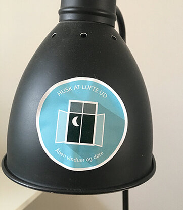 Indeklima-klistermærke Klistermærke, der minder om at huske at lufte ud for at sikre et godt indeklima, sidder på en lampe.