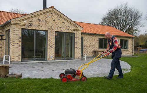 mand slår græs med benzinplæneklipper