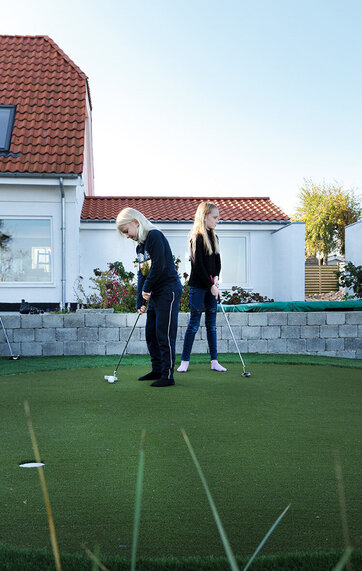 to piger spiller golf på kunstgæs i deres baghave