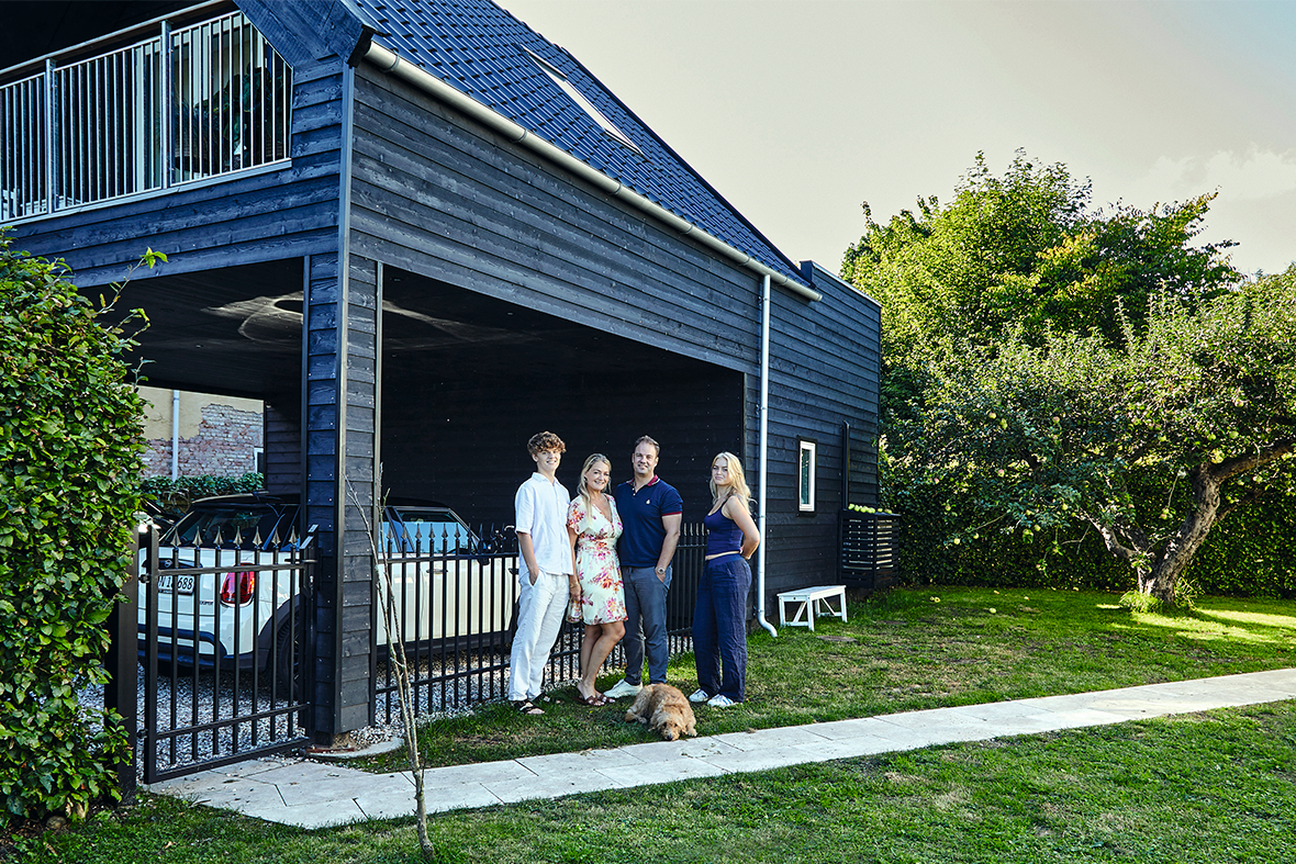 Stine Bolther og hendes familie foran deres nye annekst, der er både er carport og bolig