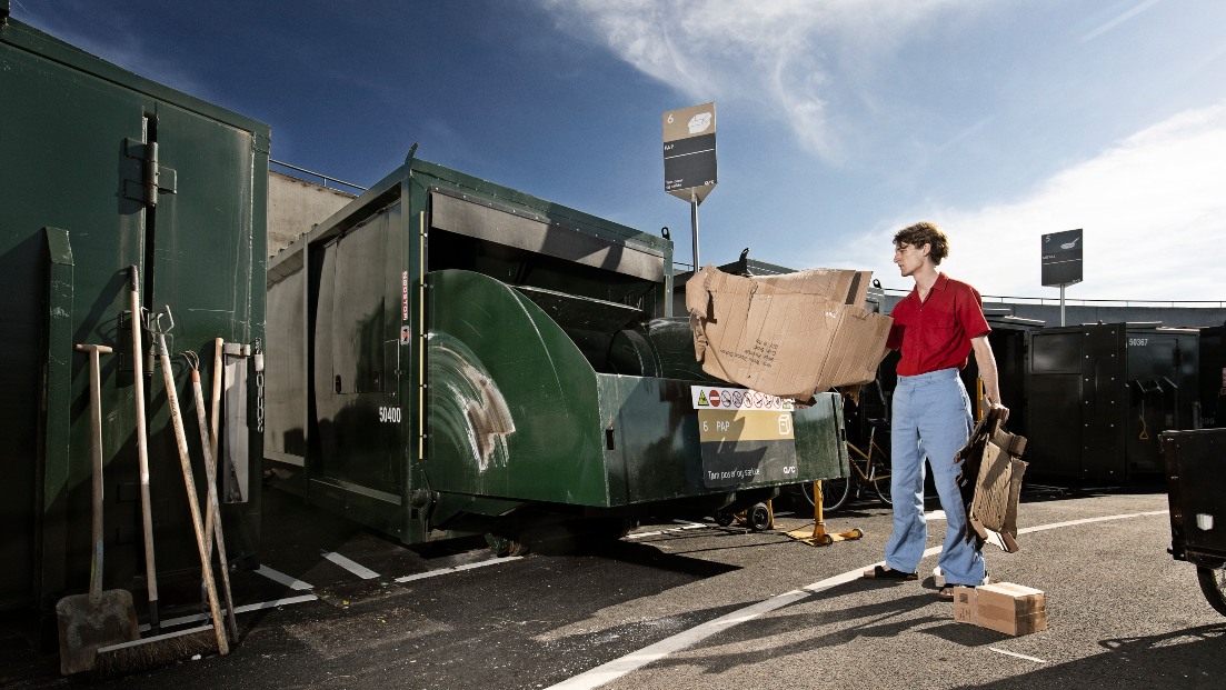 Mand smider pap i affaldscontainer